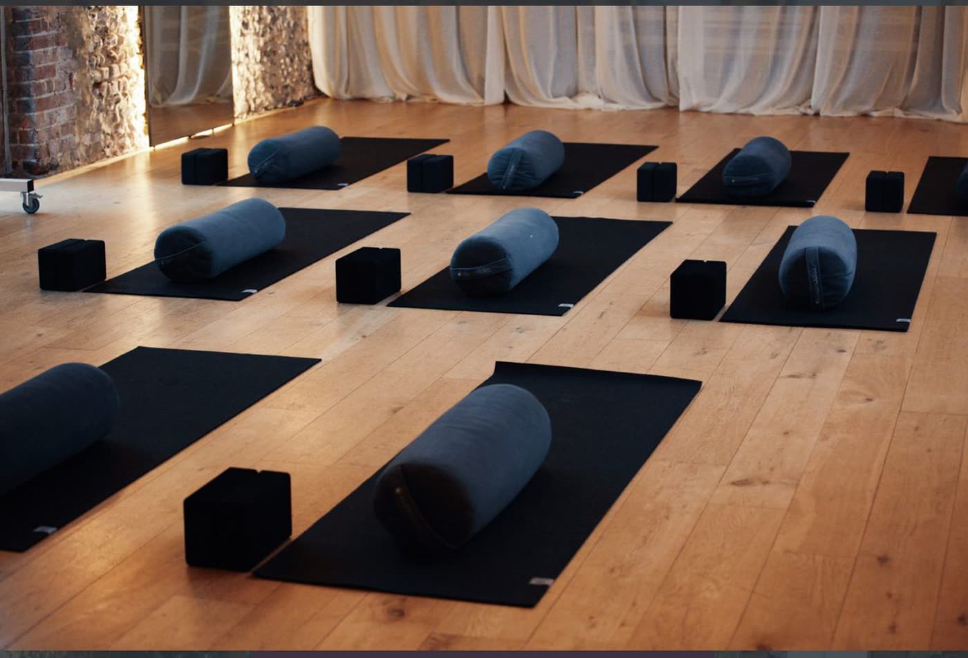 Bolsters and blocks laid out on mats across the studio floor, ready for movement