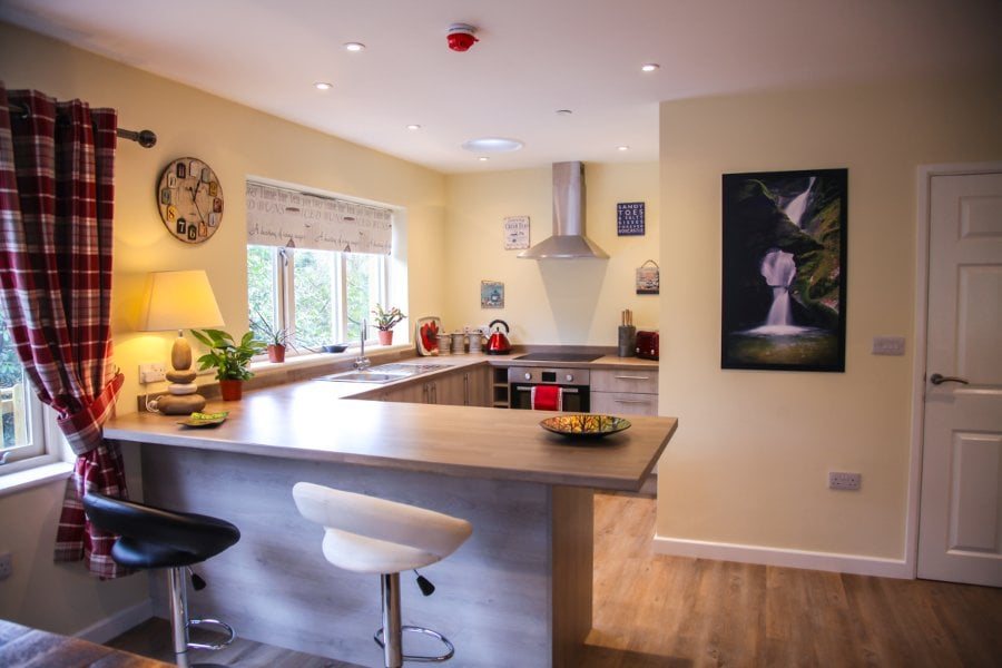 An open kitchen with a breakfast bar, window over the sink and a waterfall painting