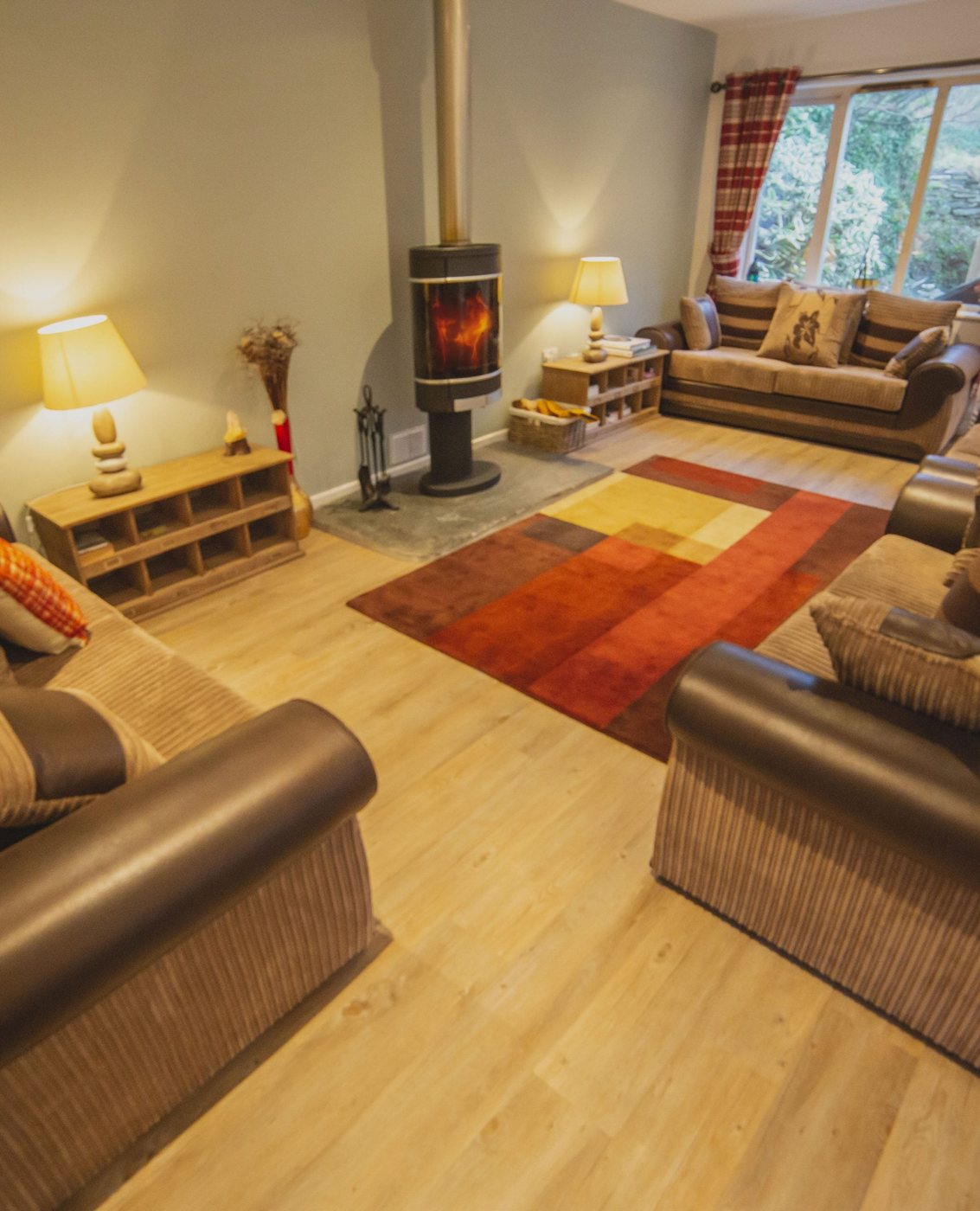 A warm living room with a wood-burning stove, sofas and lamplight